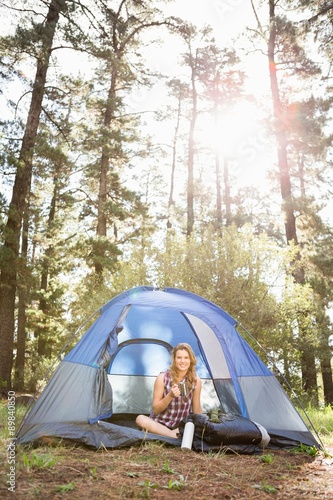 Pretty blonde camper smiling and sitting in tent