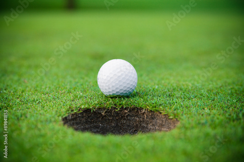 golf ball on lip of cup. Golf ball and hole
