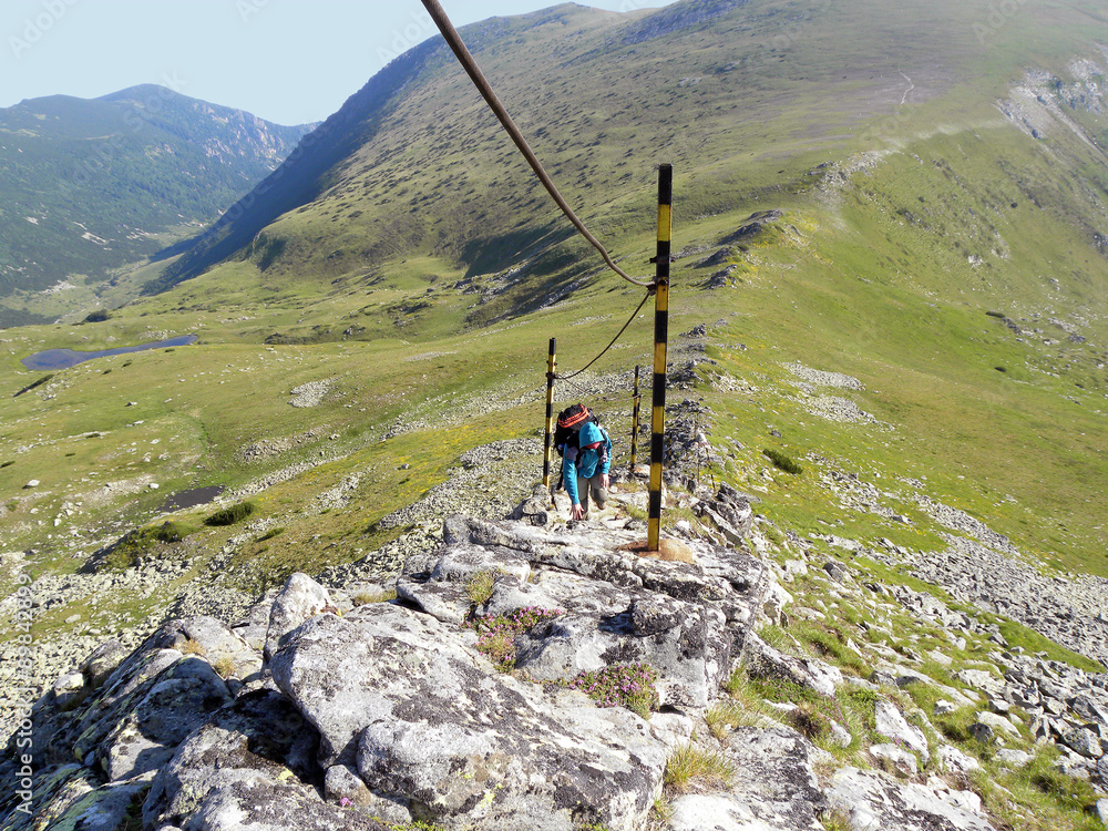 Obraz premium Young girl climbing by the safety rope on dangerous mountain slope