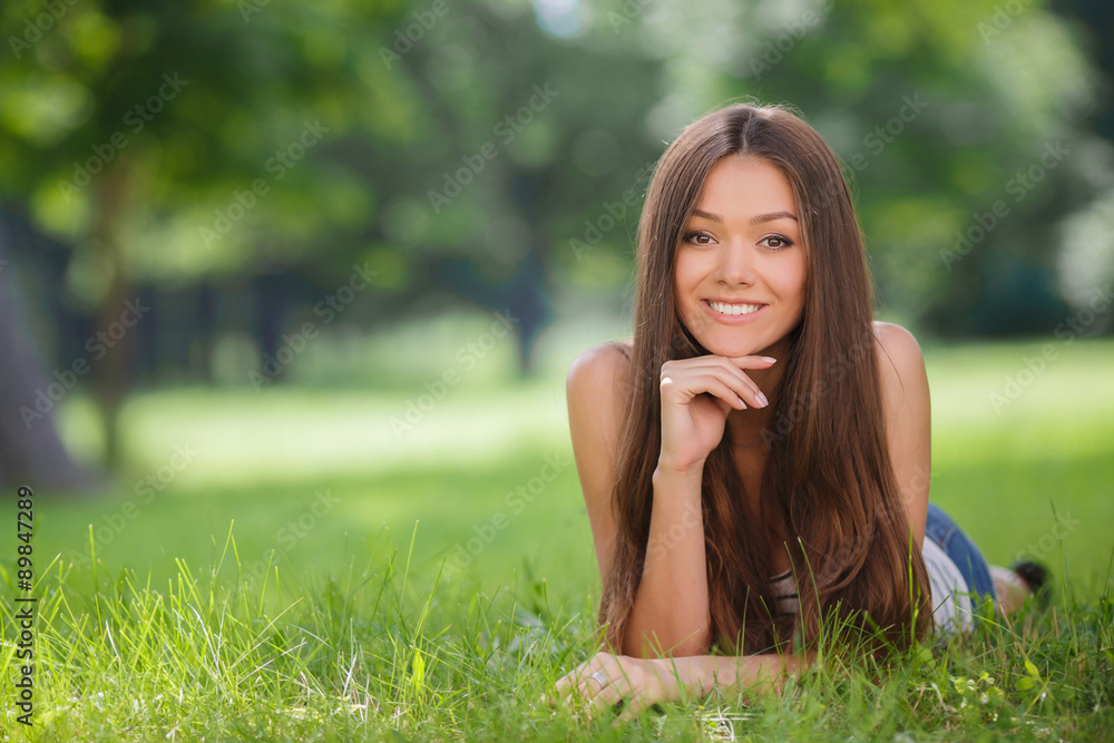 Beautiful smiling woman lying on a grass outdoor.