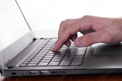 Caucasian man's finger pressing a button of a gray laptop
