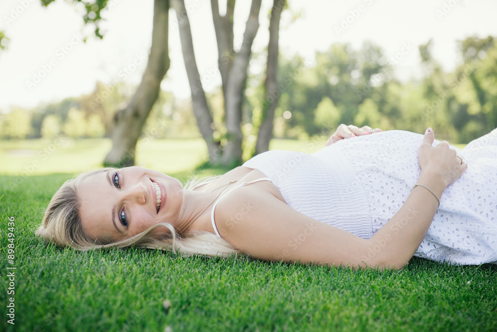 Pregnant smiling woman lie on the grass in the park Pregnant smiling woman lie on the grass in the park