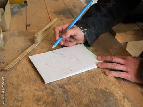 Nahaufnahme der Hände eines Tischlers, der einen Entwurf zeichnet
