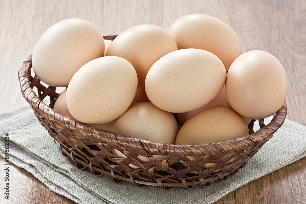 Eggs / Fresh domestic eggs in wicker basket on wooden background Eggs / Fresh domestic eggs in wicker basket on wooden background
