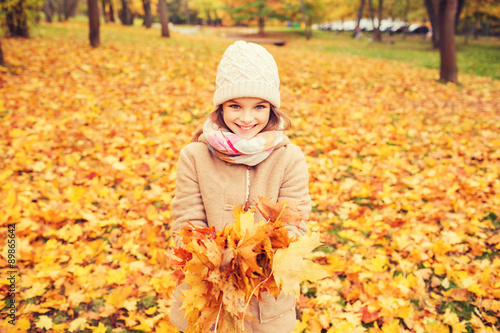 smiling little girl with autumn leaves in park