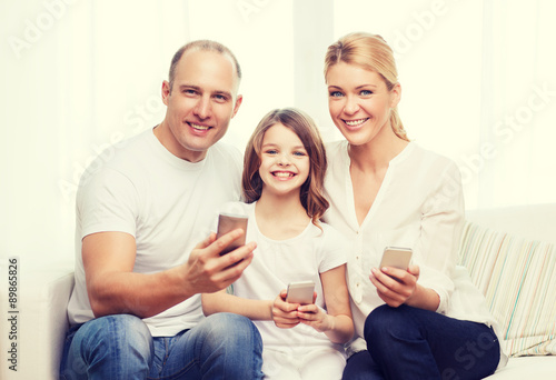 parents and little girl with smartphones at home