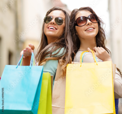 two girls in sunglasses with shopping bags in ctiy