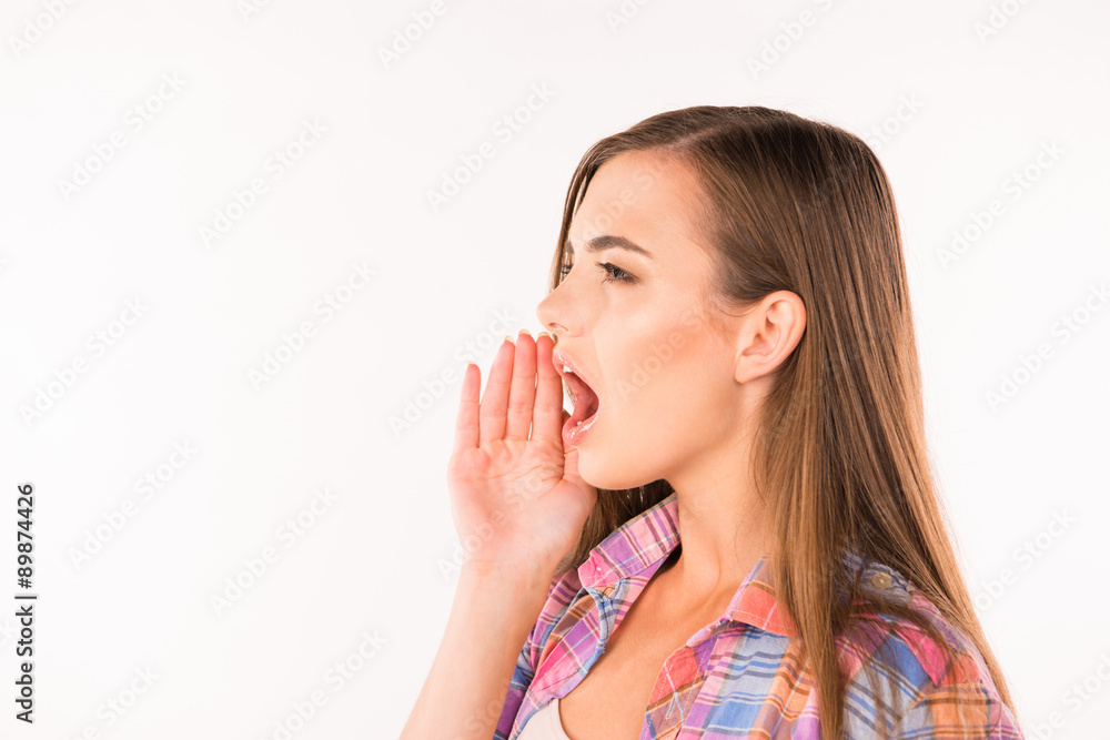 Great news! Cheerful young woman in shirt holding hand near mout Great news! Cheerful young woman in shirt holding hand near mout