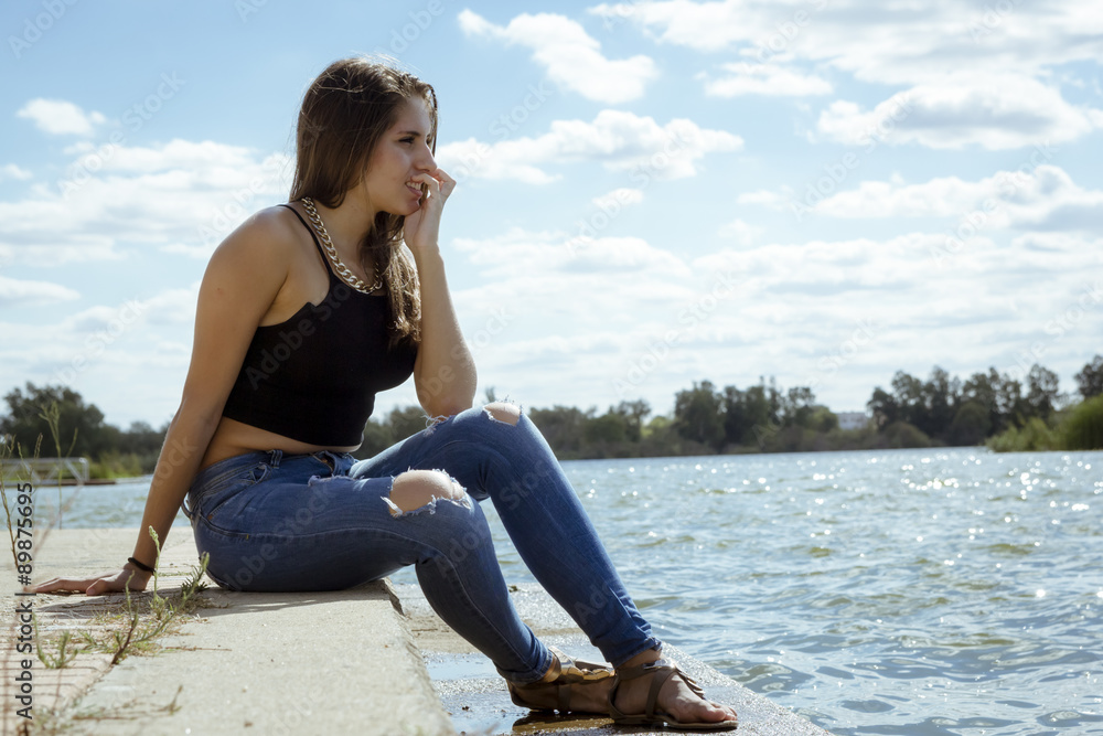 Chica adolescente posando en el embarcadero. Adolescente rubia de quince años como modelo. Chica rubia de pelo largo al lado del rio en verano. Chica adolescente posando en el embarcadero. Adolescente rubia de quince años como modelo. Chica rubia de pelo largo al lado del rio en verano.