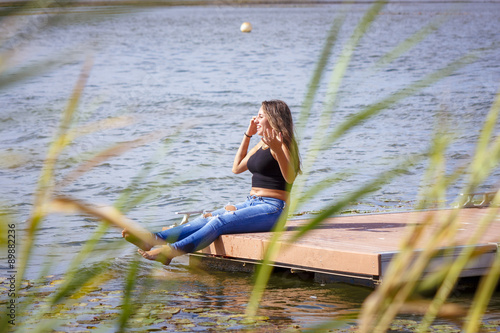 Fototapeta Naklejka Na Ścianę i Meble -  Adolescente de 15 años en el embarcadero. Chica rubia adolescente pasando una tarde de verano junto al rio.