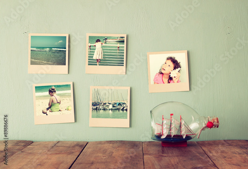 instant photos hang over wooden textured background next to decorative boat