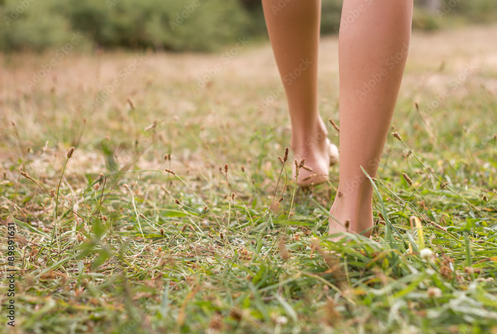 Back view of female legs walking on the grass