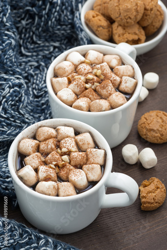 Two cups of cocoa with marshmallows on wooden table, vertical