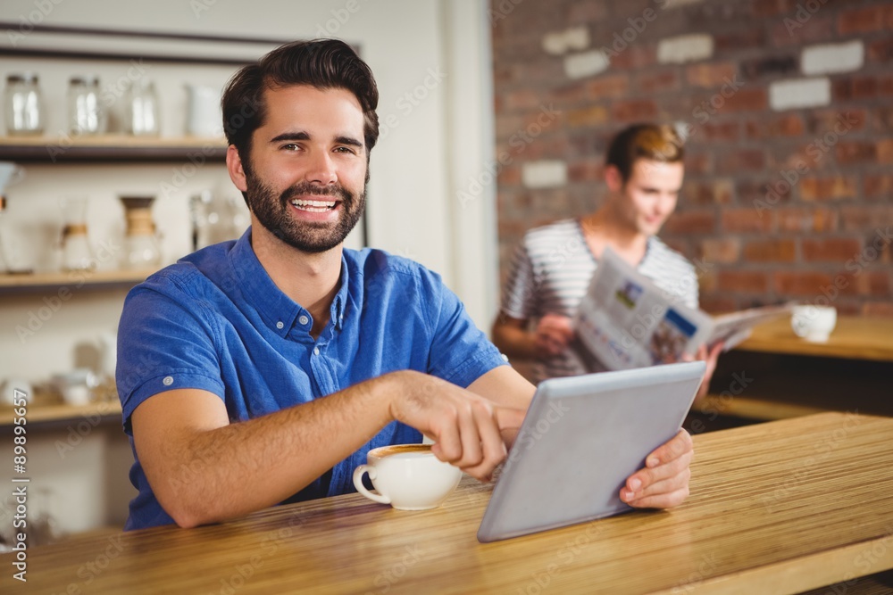 Fototapeta premium Young man having cup of coffee using tablet
