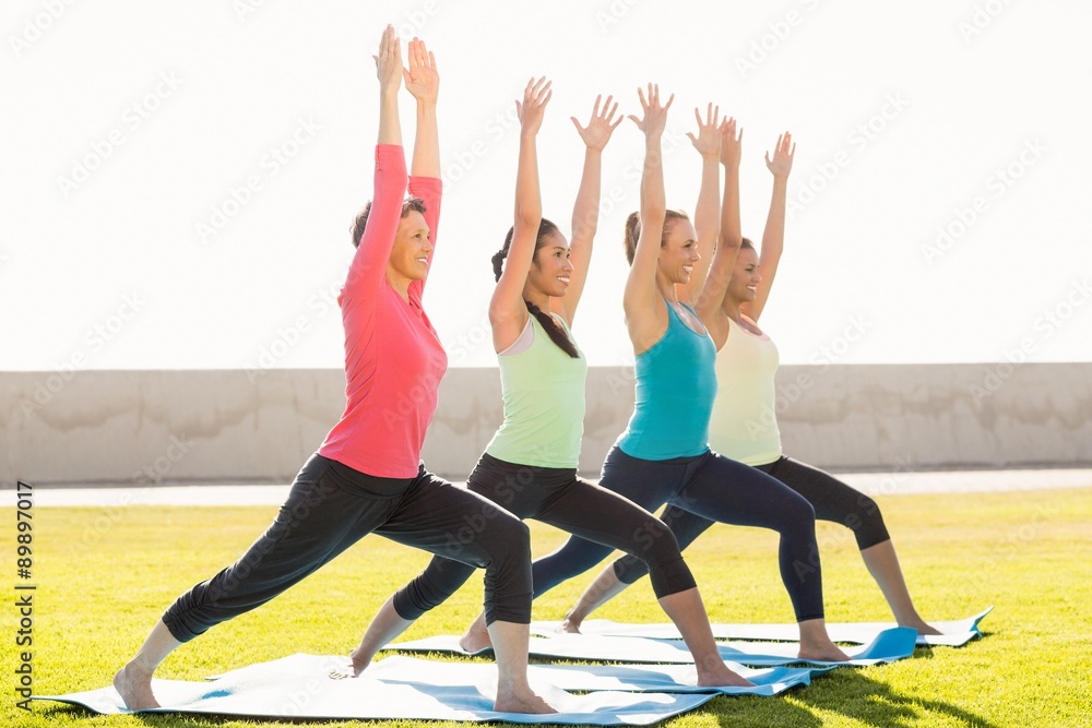 Smiling sporty women doing warrior pose in yoga class Smiling sporty women doing warrior pose in yoga class