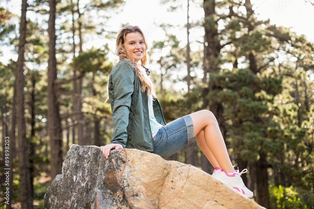 Young happy jogger sitting on rock and looking at camera