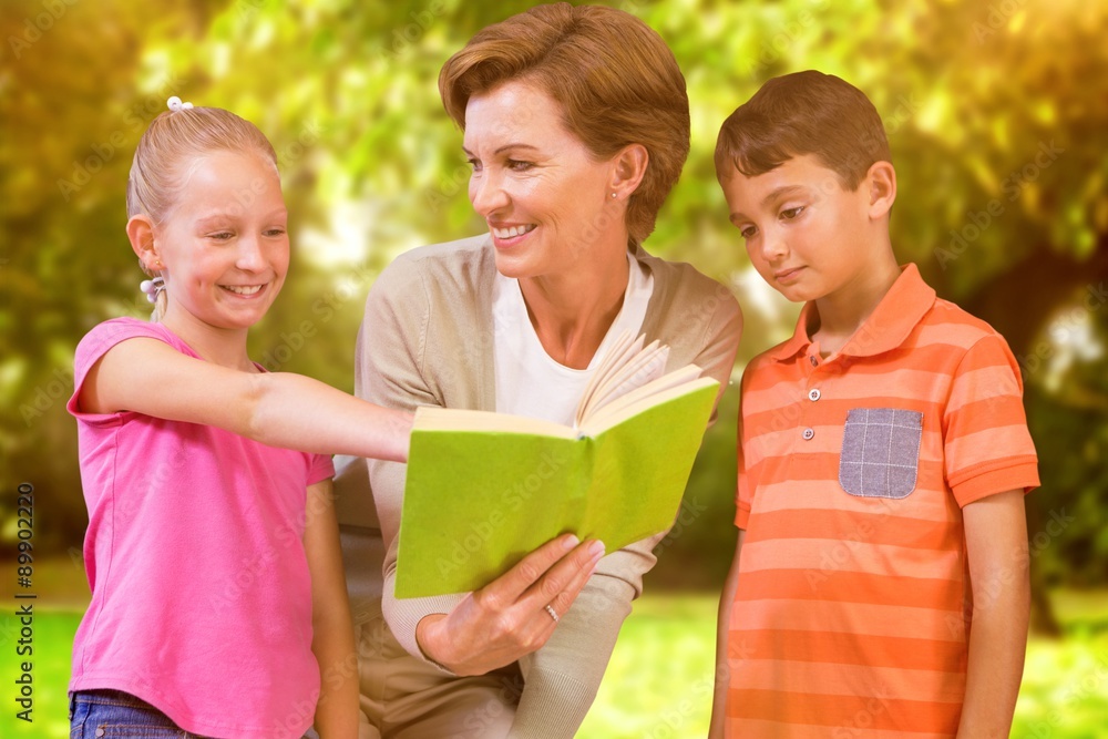 Composite image of teacher reading book with pupils at library Composite image of teacher reading book with pupils at library