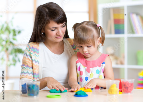 Young woman and kid playing with colorful clay molding different