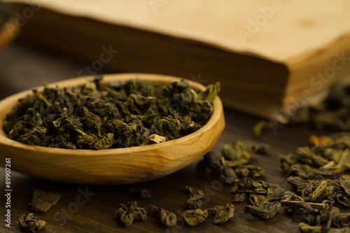 Oolong tea in wooden spoon on a background of old vintage books. Menu, recipe