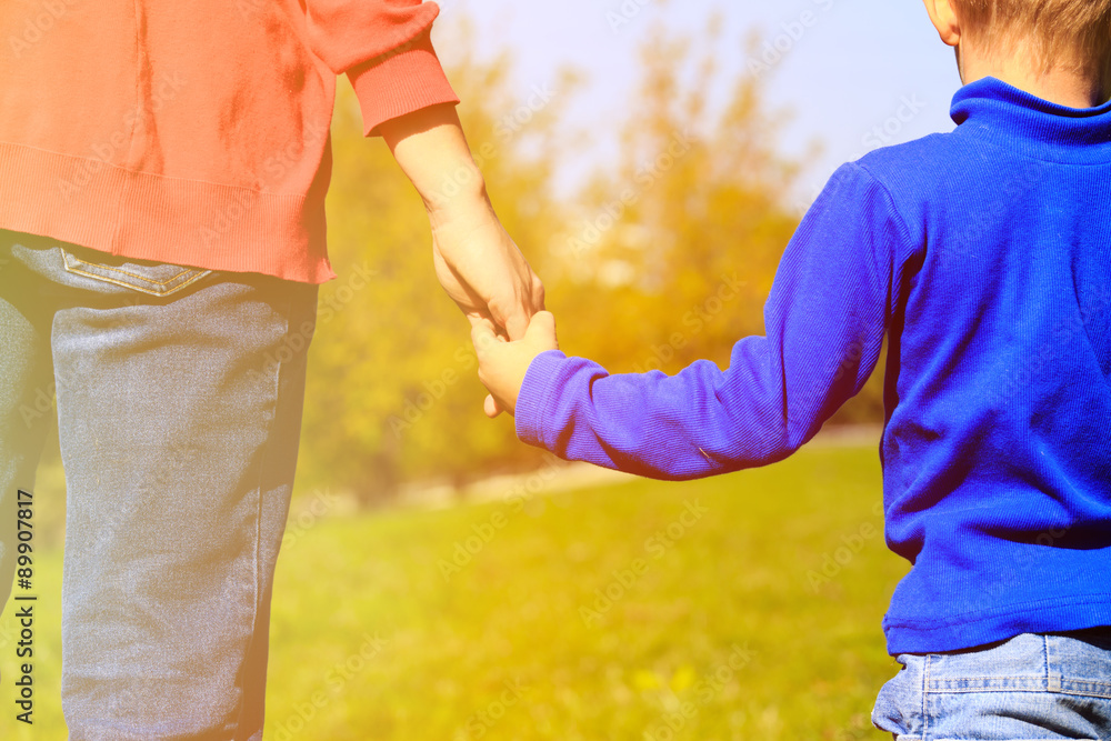 Mother holding hand of her son outdoors Mother holding hand of her son outdoors