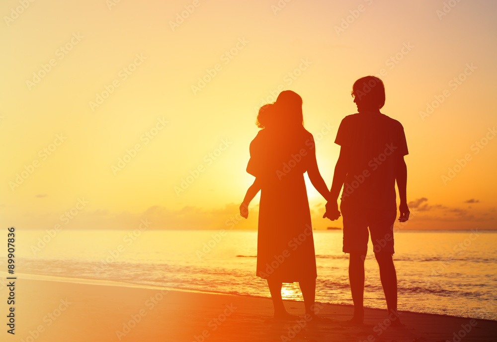 romantic couple with little child at sunset tropical beach