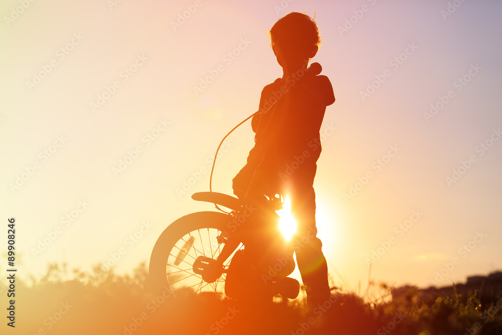 Fototapeta premium little boy riding bike at sunset