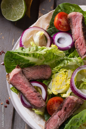 Mexican tortillas with green fresh salad filling, beef, onions, tomatoes with gucamole and tortilla chips on te vintage board photo