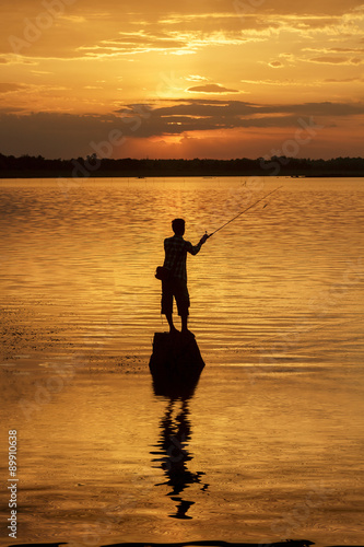 Silhouette fisherman of Lake in action when fishing.
