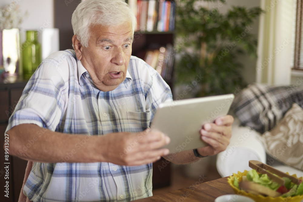 Shocked senior man holding his tablet Shocked senior man holding his tablet
