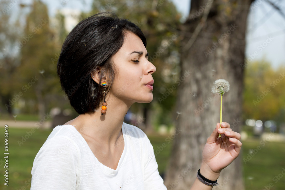 Girl blowing on white dandelion in the park Girl blowing on white dandelion in the park