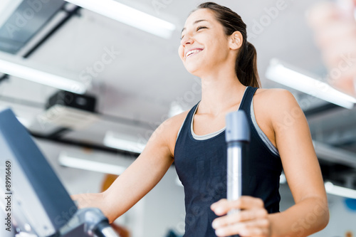 Beautiful young lady using the elliptical trainer
