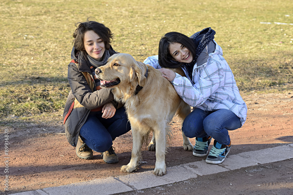 Two friends walking the dog in a park Two friends walking the dog in a park
