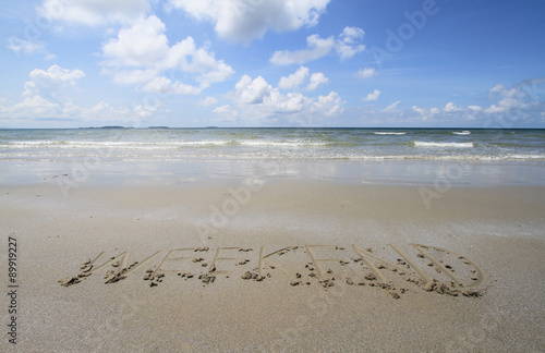 Word "WEEKEND" handwritten in sand on a beach