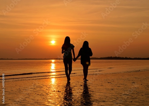 Silhouette of friends walking togetther at sunset on the beach