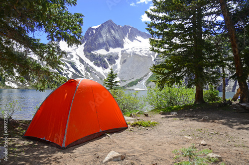 Camping tent in the mountains with lake and snow capped peaks