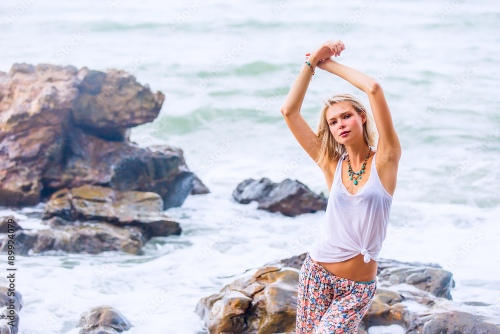 Beautiful young blonde woman posing outdoor at the rocky sea shore Beautiful young blonde woman posing outdoor at the rocky sea shore