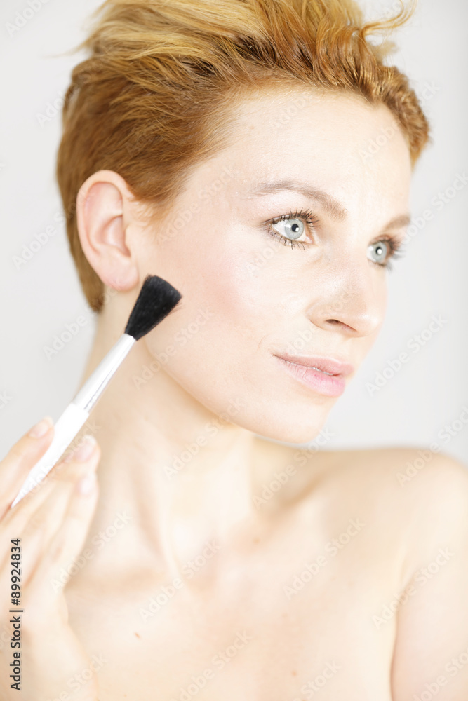 Young woman applying make up