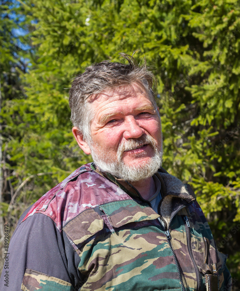 Fototapeta premium Portrait of a hunter with a gray beard on a background of green