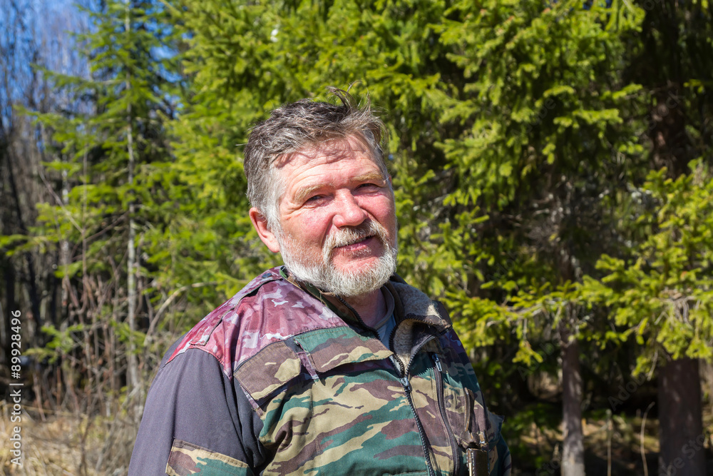 Portrait of a hunter with a gray beard on a background of green