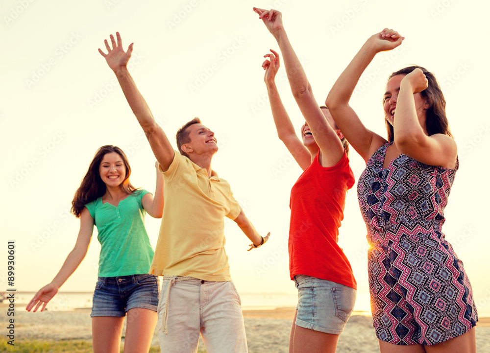 Obraz premium smiling friends dancing on summer beach