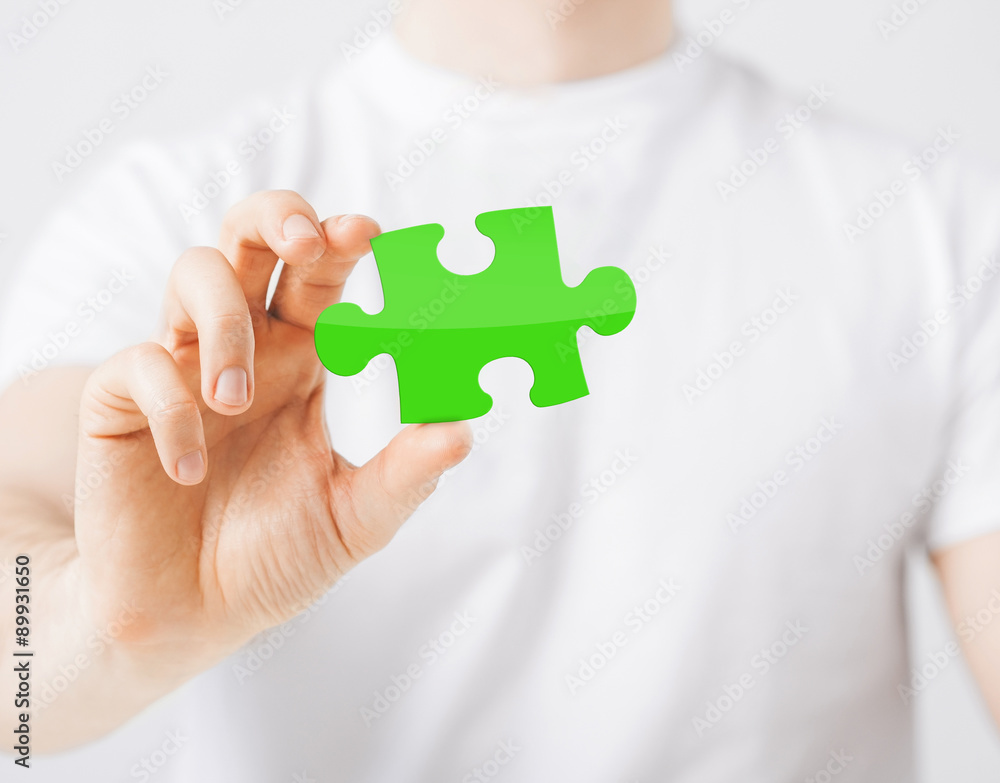 close up of man holding green puzzle piece close up of man holding green puzzle piece