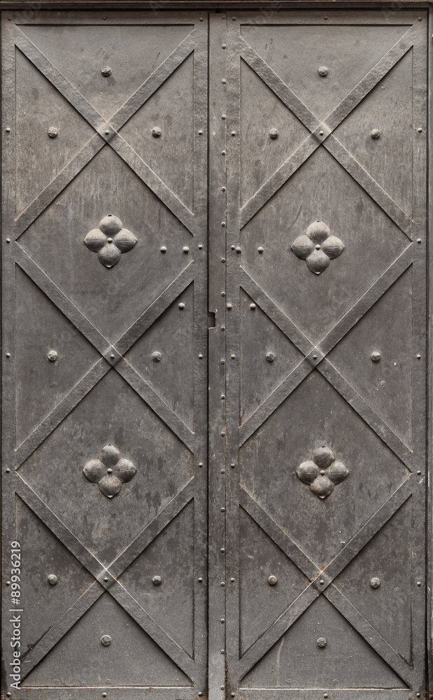 Old iron door reinforced with decorative steel belts painted black Old iron door reinforced with decorative steel belts painted black