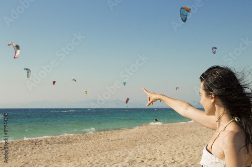 Young woman points the finger at kitesurfing kites on the beach