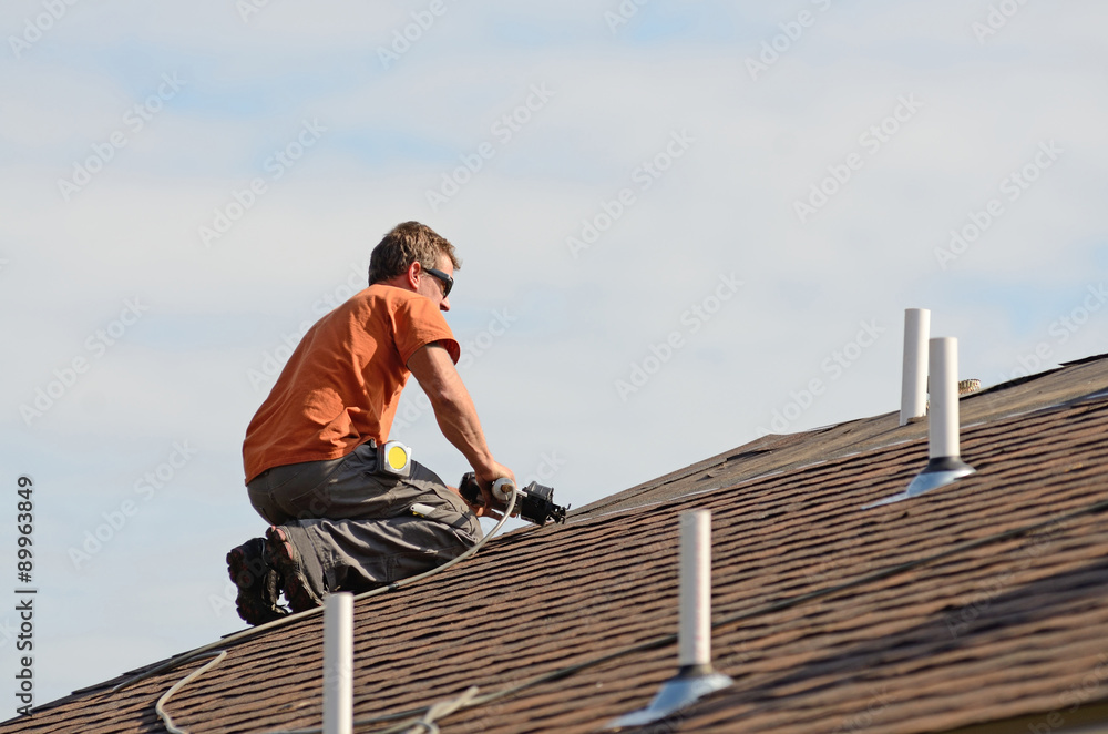 Fototapeta premium Building contractor putting the asphalt roofing on a large commercial apartment building.