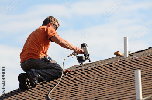 Obraz na plátně Building contractor putting the asphalt roofing on a large commercial apartment building
