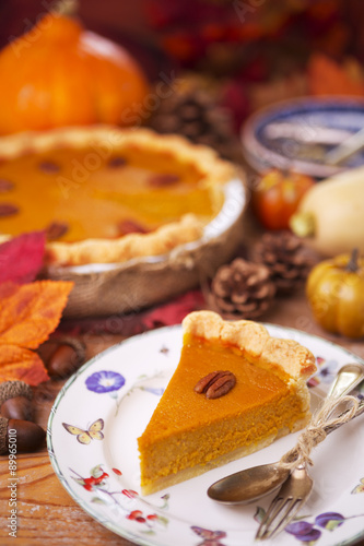 Homemade pumpkin pie on a rustic table with autumn decorations photo