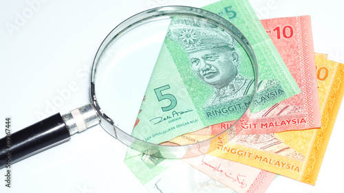 Magnifier with Malaysia bank notes.concept photo.