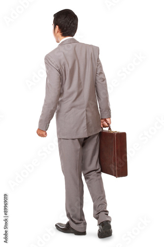 back view of a business man standing and holding a briefcase, isolated on white background