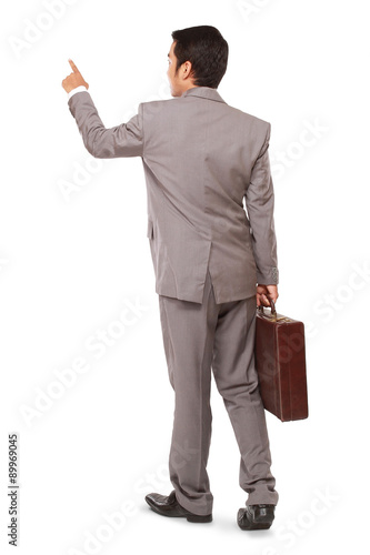 Rear view of a businessman standing pointing and holding bag, isolated on white background