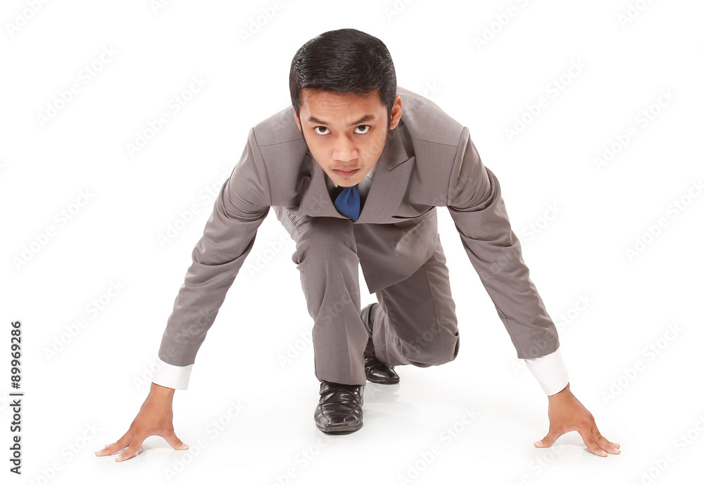 young businessman kneeling as if about to start a race, isolated on white background young businessman kneeling as if about to start a race, isolated on white background